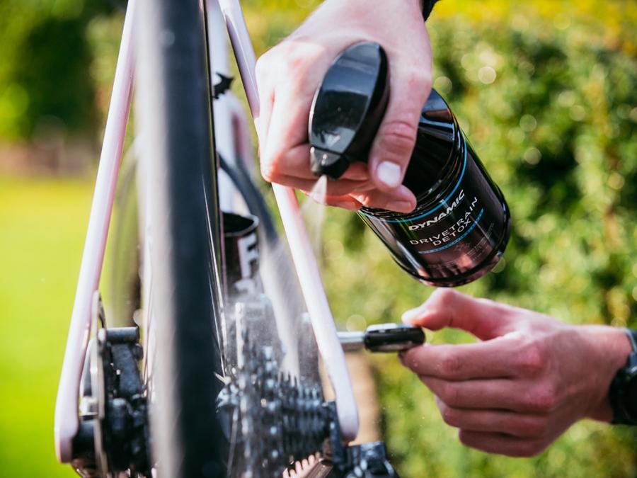 Dynamic Bio Drivetrain Detox (1 Ltr), shown near a dirty bike chain, demonstrating its power to break down stubborn oil and grime.